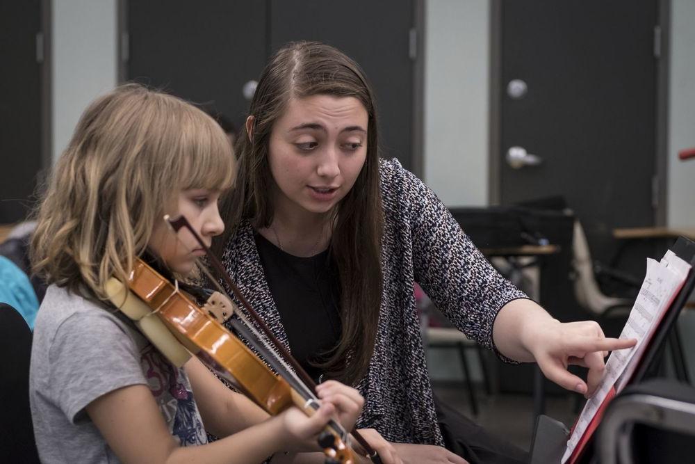 一名威尼斯人赌场网站音乐学生在小提琴课上与一名小学生一起工作.